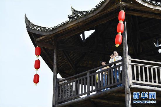  游客在重慶市武隆區(qū)黃鶯鄉(xiāng)復(fù)興村的觀景樓上欣賞田園景色（2019年3月28日攝）。 新華社記者 劉潺 攝
